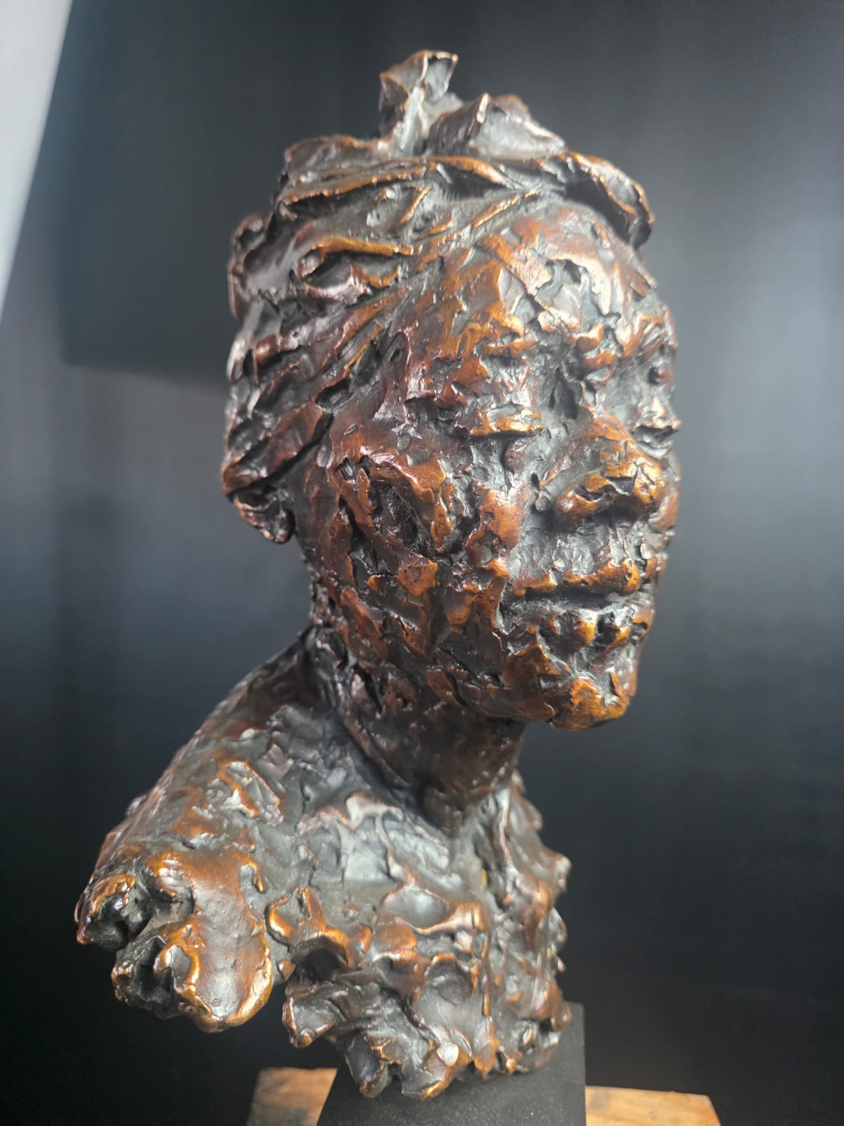 A bronze bust photographed against a dark studio wall