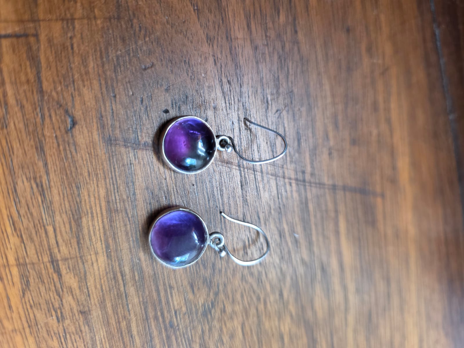 A pair of amethyst drop earrings photographed on a wooden table